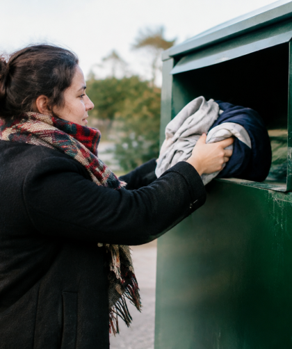 Main deposant vetement dans bac de collecte